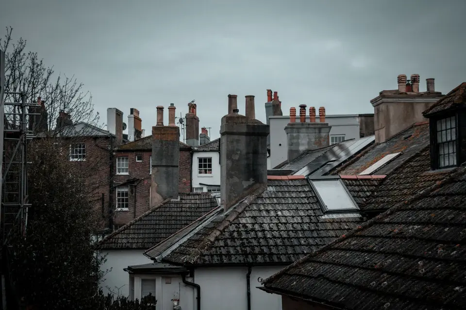 Toits d'ardoise et souches de cheminées en brique sous un ciel gris